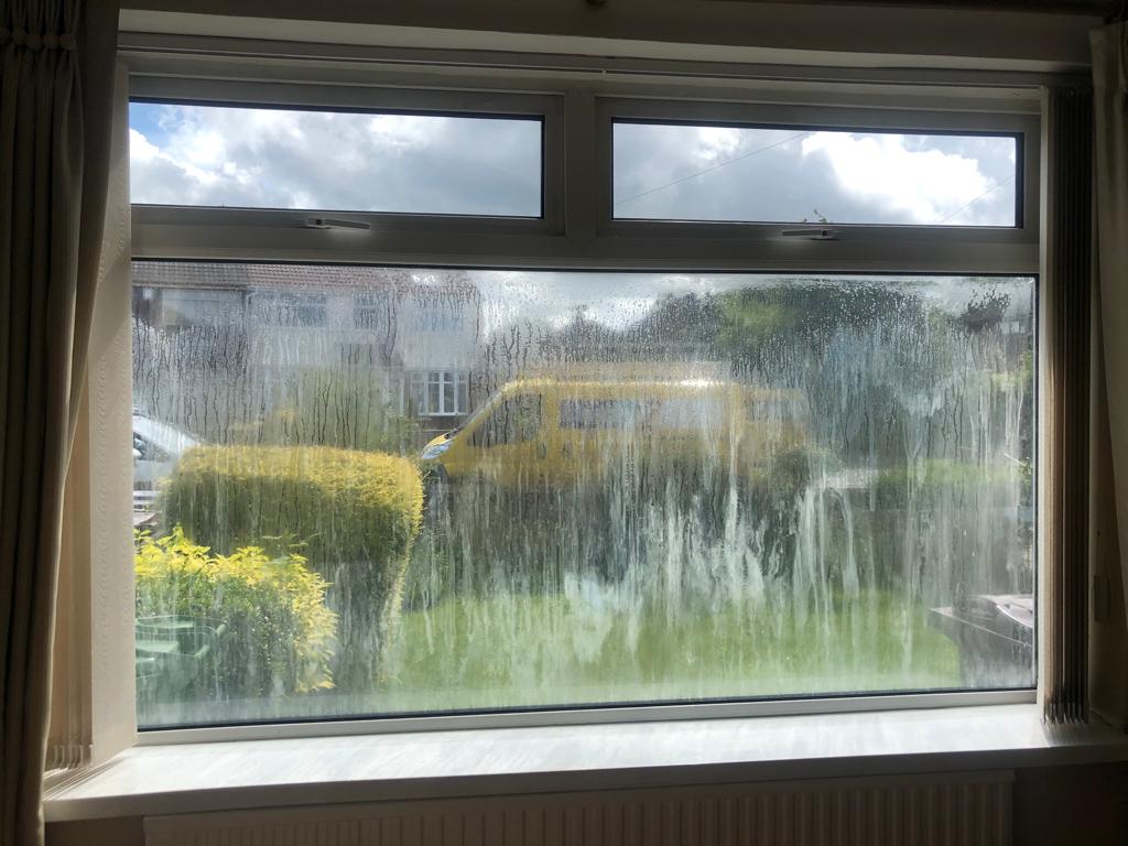 Image of cloudy window looking with a blurred view of the garden.