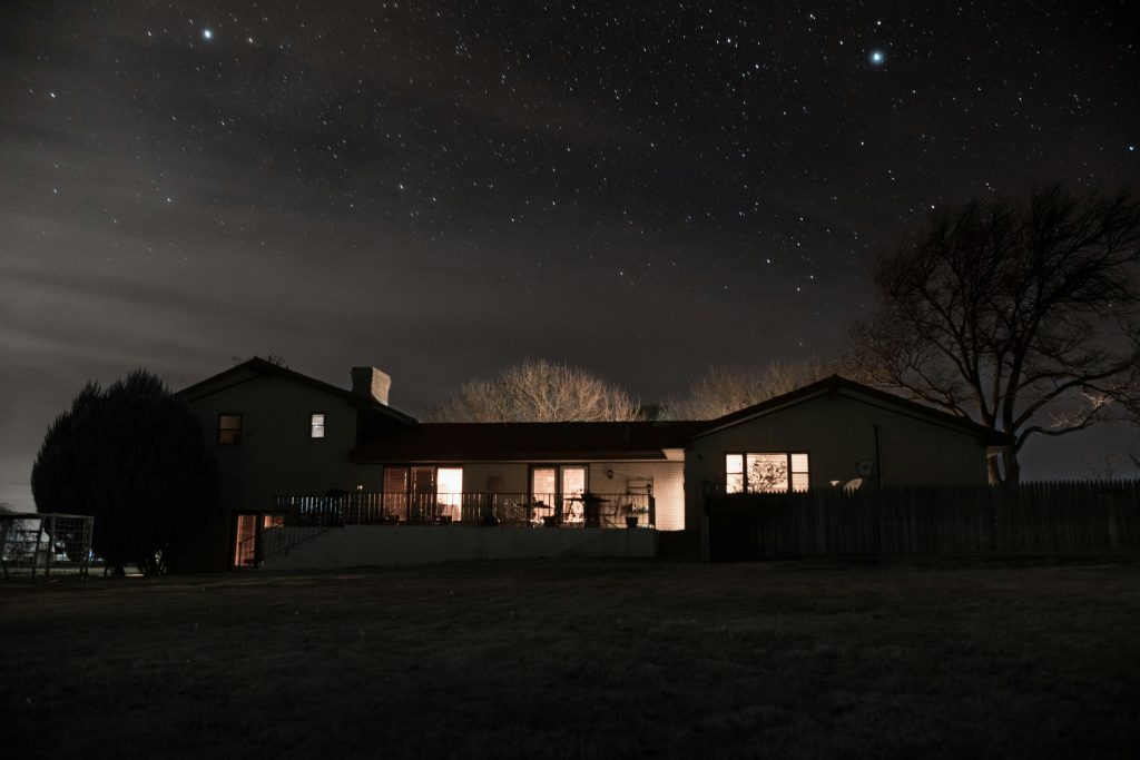 Detached house at night with lights on.